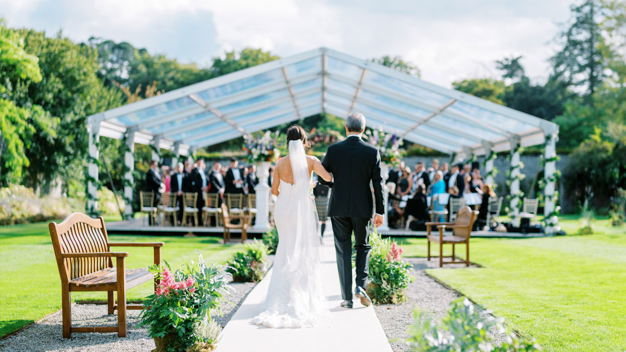 Bride walking up the aisle in the Adare Manor gardens